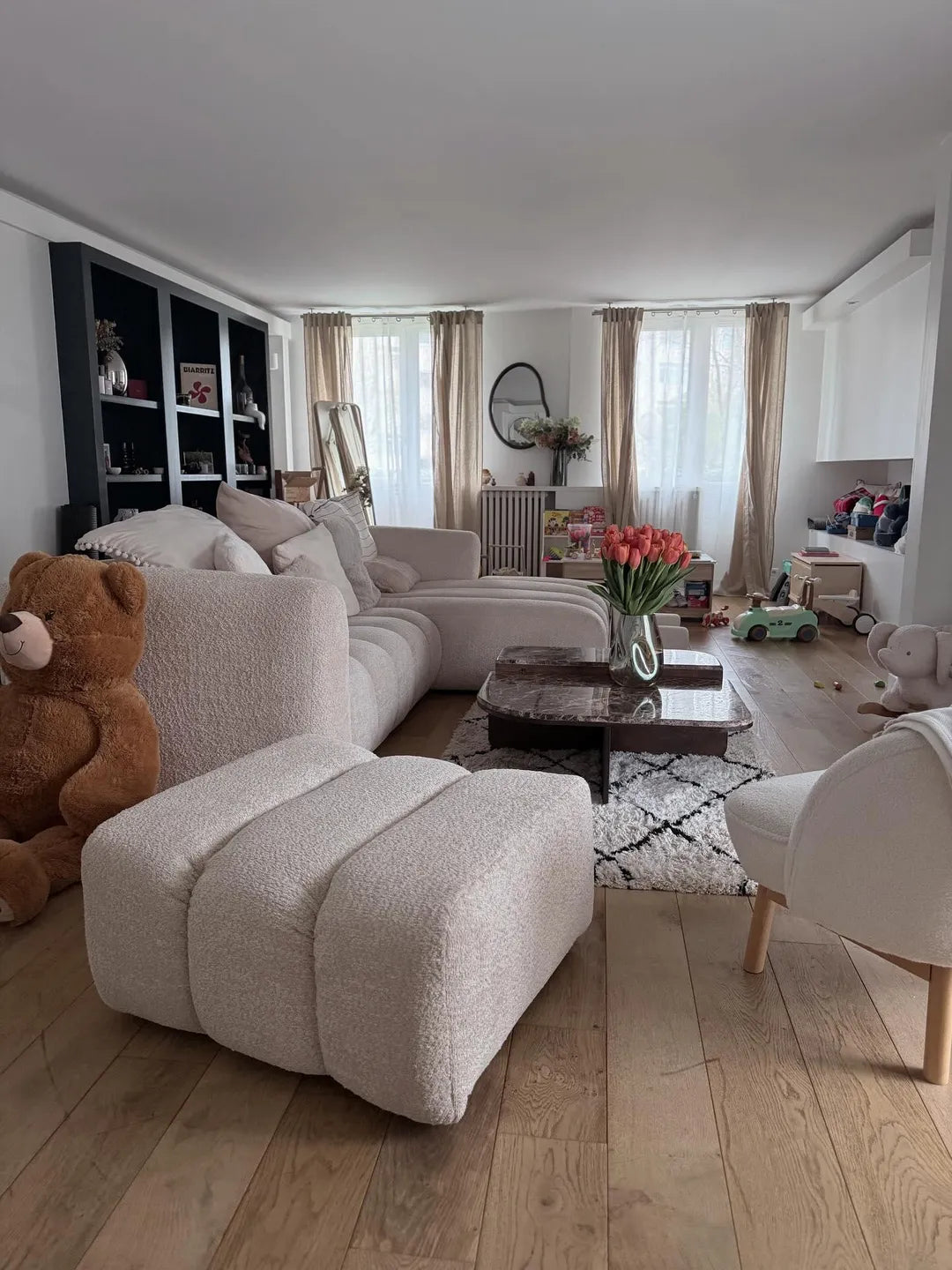 Canapé d’angle bouclette écru et pouf assorti dans un salon familial