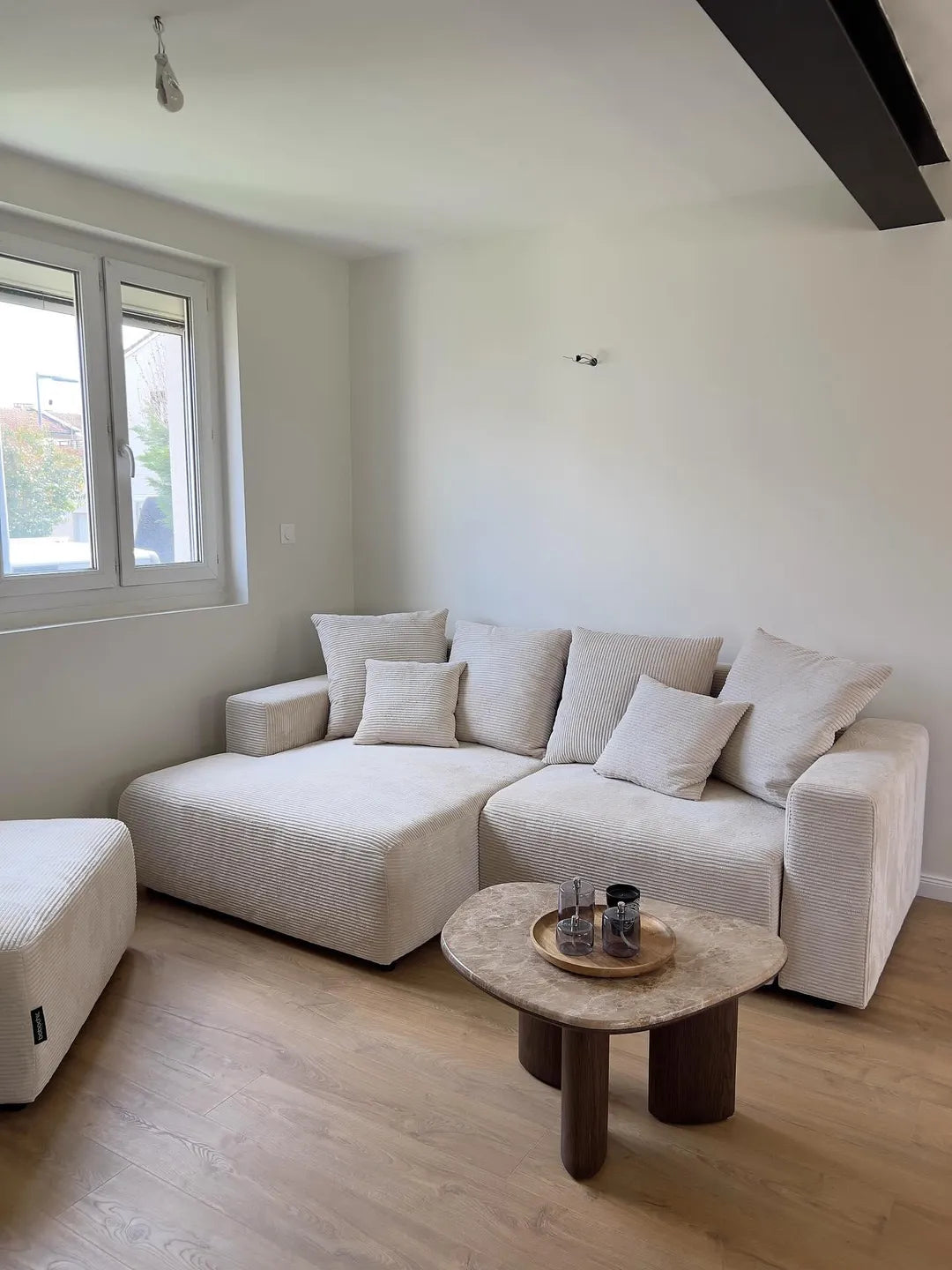 Canapé d’angle écru en velours côtelé avec pouf et table basse en marbre